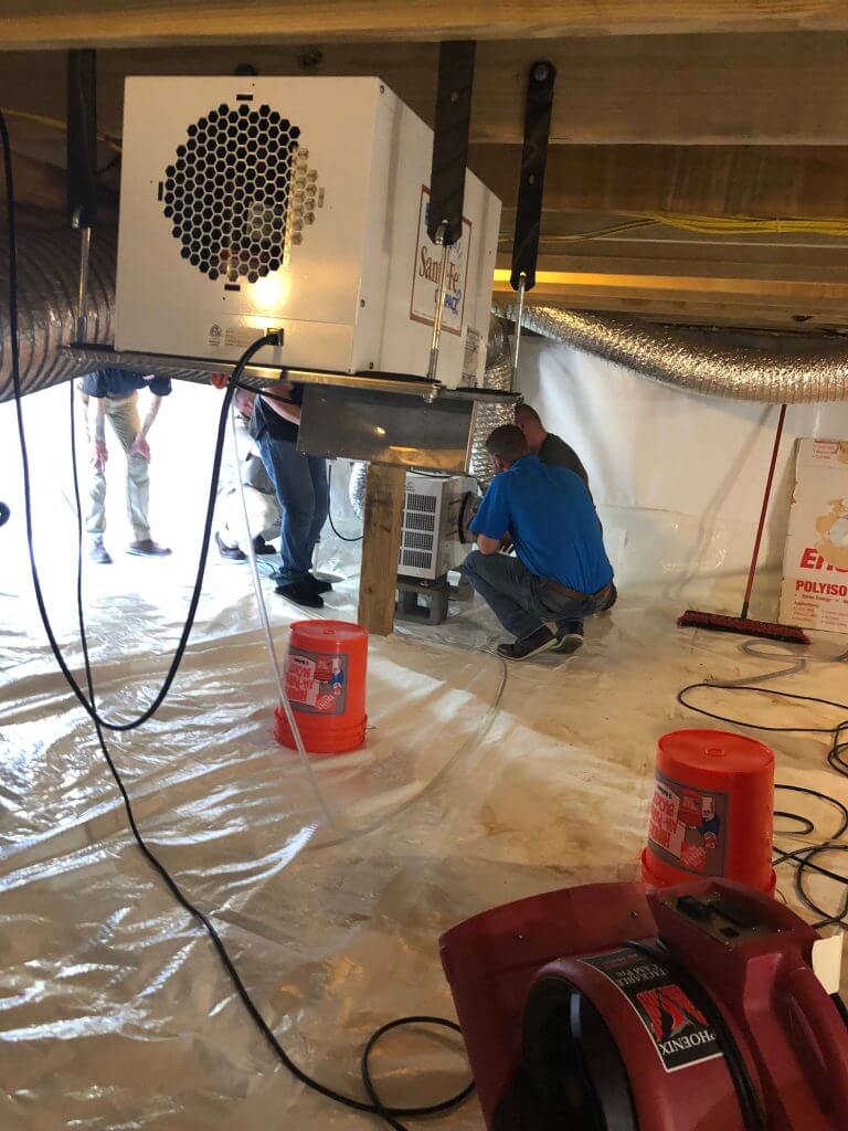 An insulation crew working on a crawl space