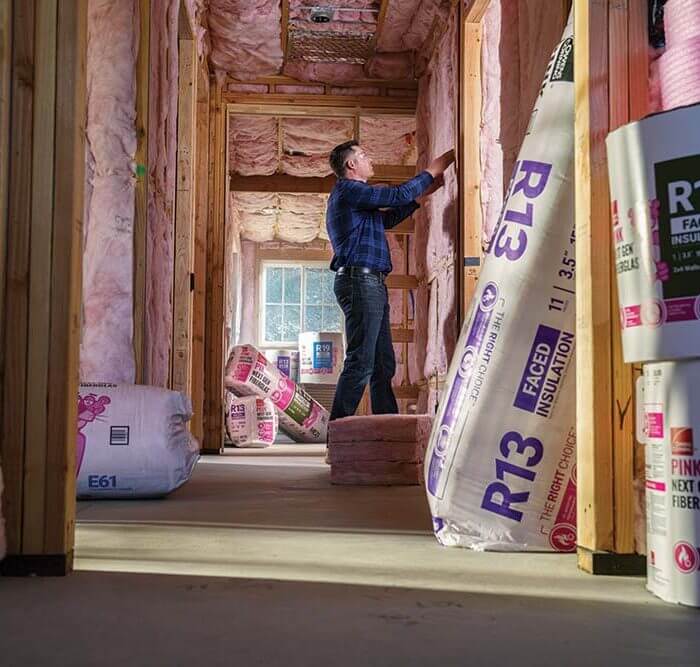 man installing Owens Corning® PINK Next Gen™ Fiberglas™ Insulation on wall