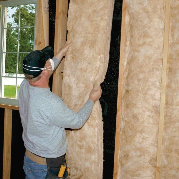man installing CertainTeed Fiberglass Batt insulation on wall