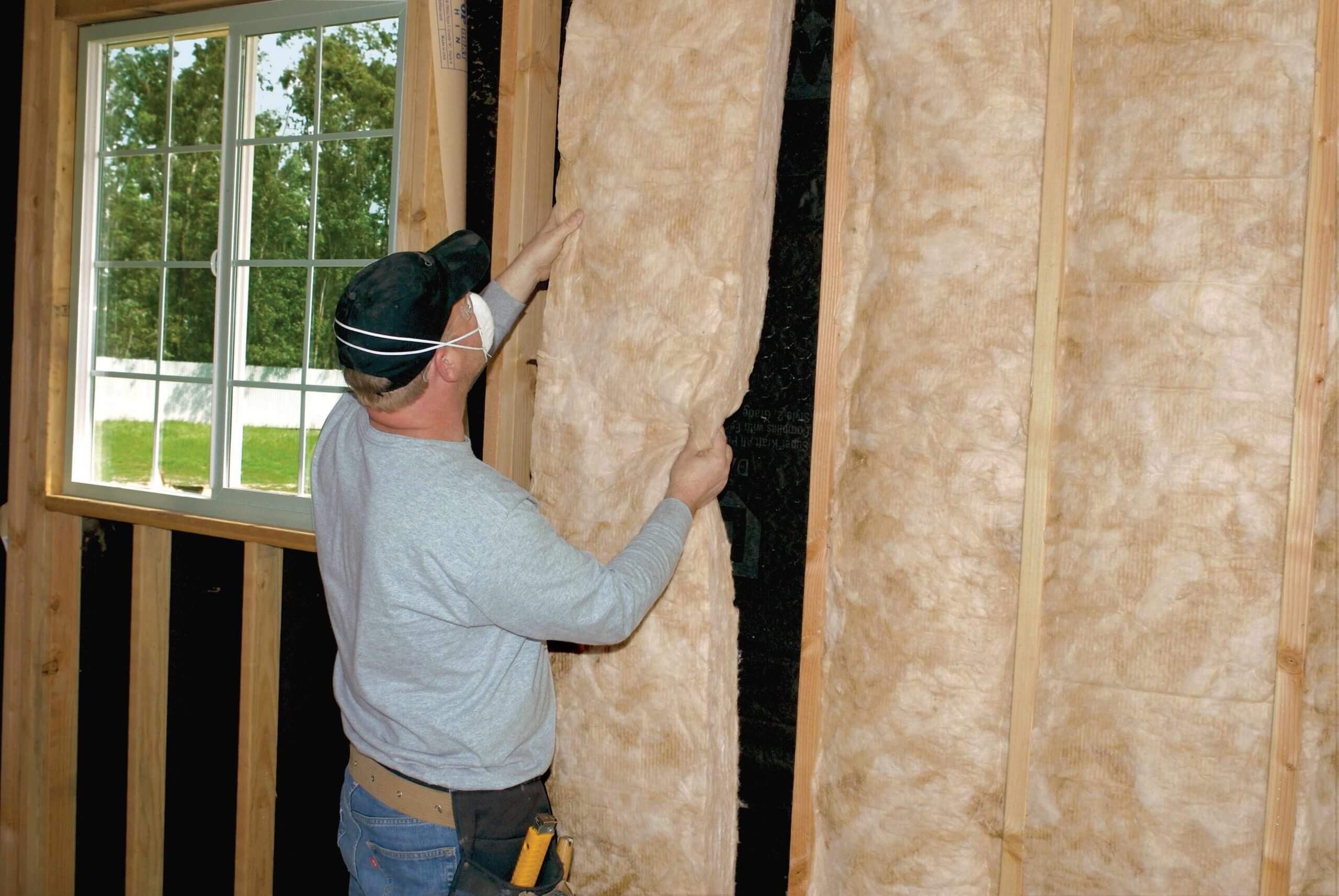 man installing CertainTeed Fiberglass Batt insulation on wall