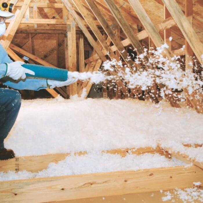 man blowing insulation in attic