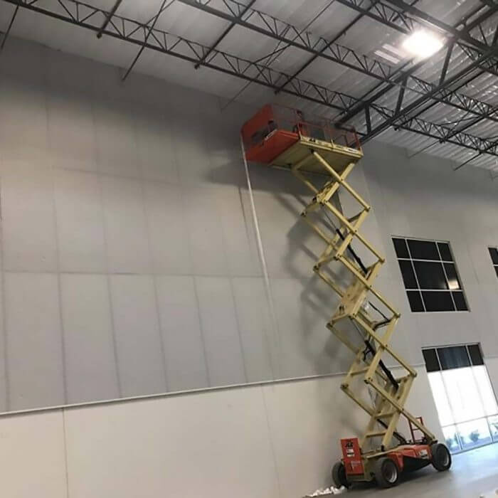 scissor lift fully extended to finished insulation in metal building