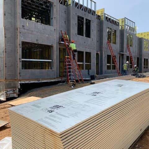 2 construction workers installing OX-IS insulation on a newly built building