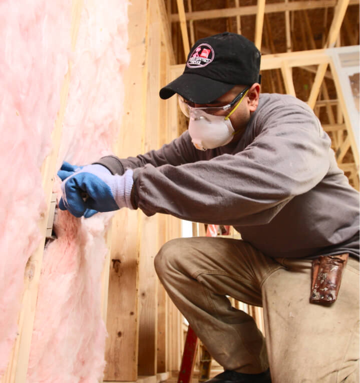 Man installing pink fiberglass insulation