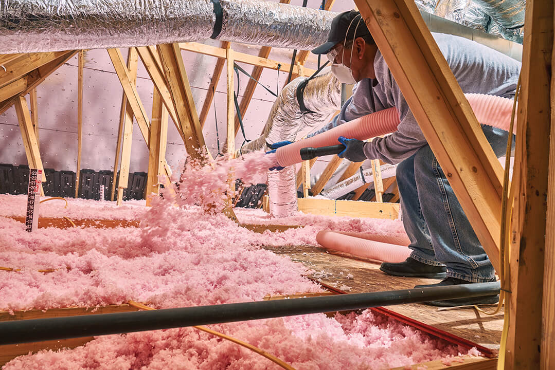 Technician using tube hose to spray pink foam insulation