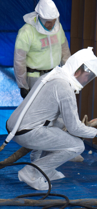 2 men in overalls and ventilation hoods doing IDI training