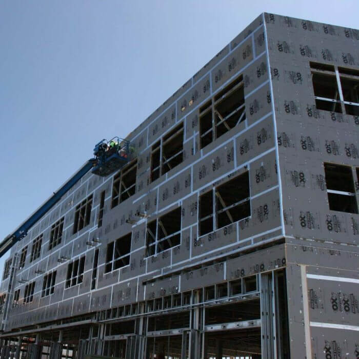 Two construction workers in blue boom lift working on unfinished building