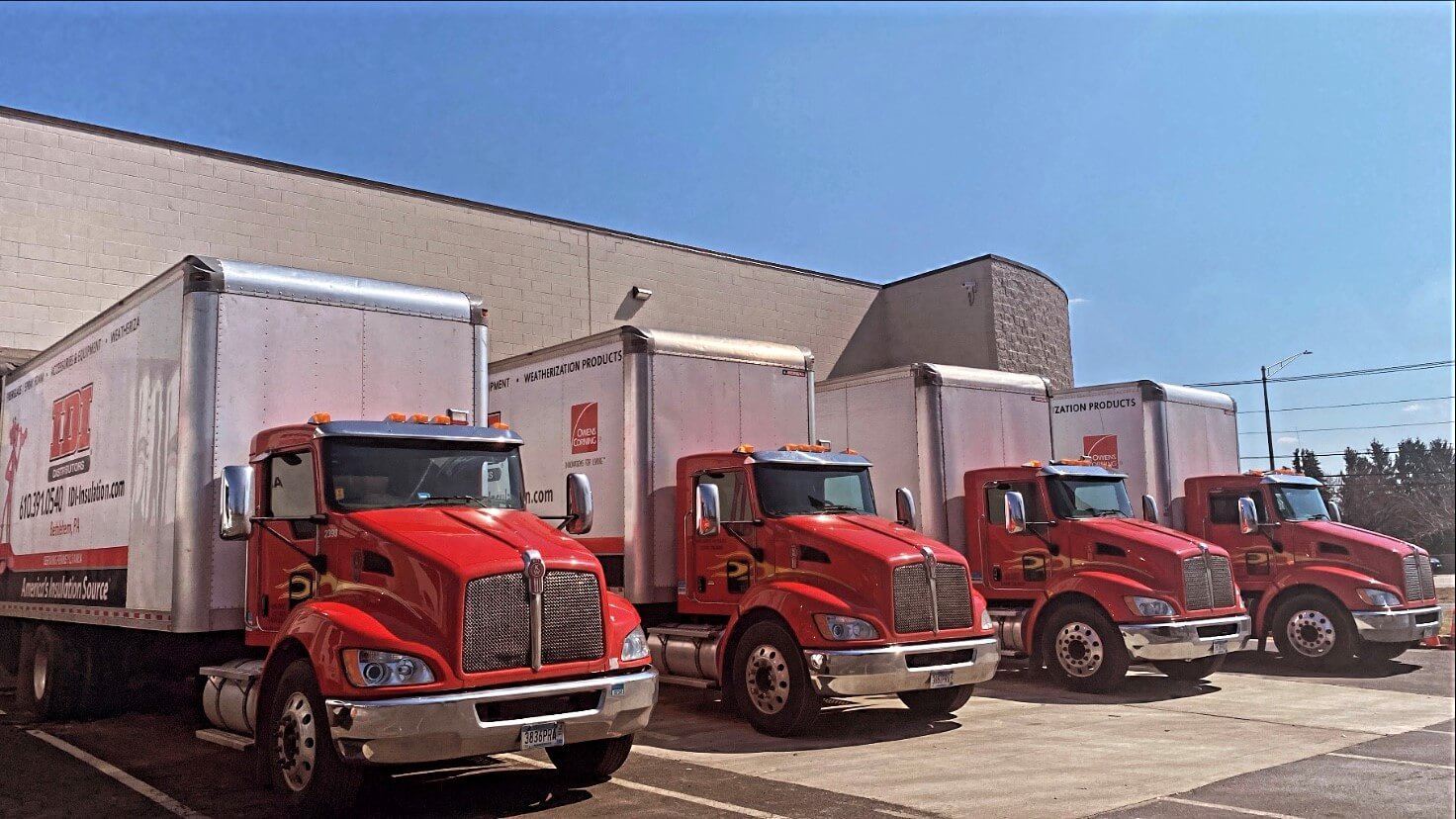 Four red-fronted IDI semi trucks parked in a line