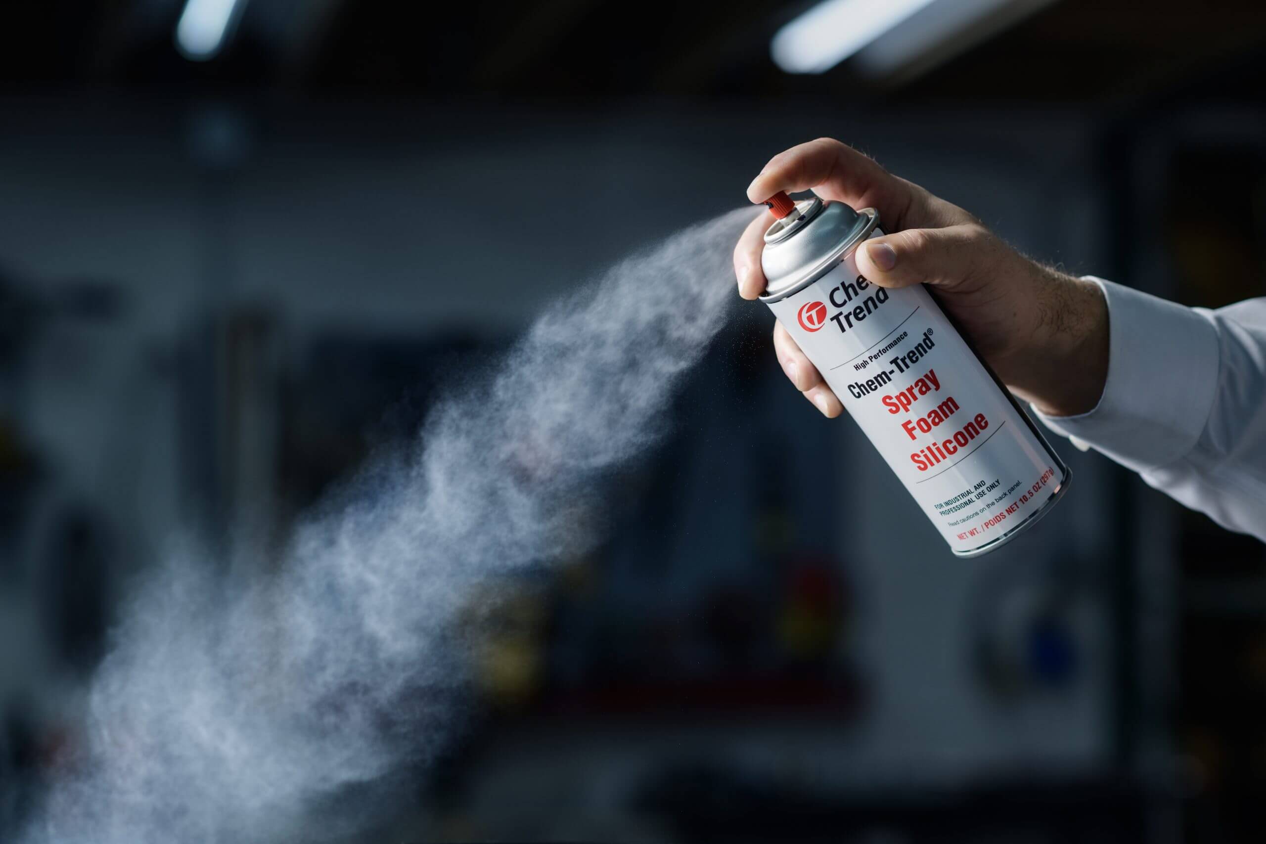 A hand spraying Chem-Trend Spray Foam Silicone from a canister.