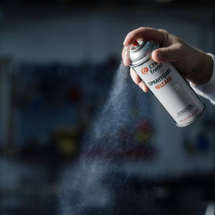 A hand spraying Chem-Trend Spray Foam Silicone from a canister.