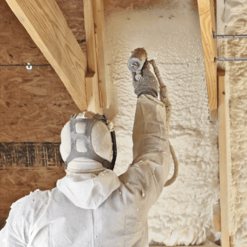 Person reaching above their head to spray foam insulation