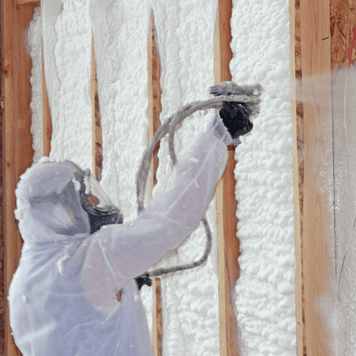 Person standing upright and spraying foam insulation above their head