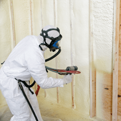 Person bending over to spray foam insulation