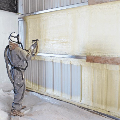 Person in grey protective suit spraying foam insulation