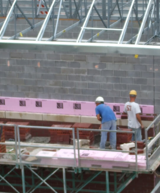 Two men in t-shirts and hard hats installing insulation