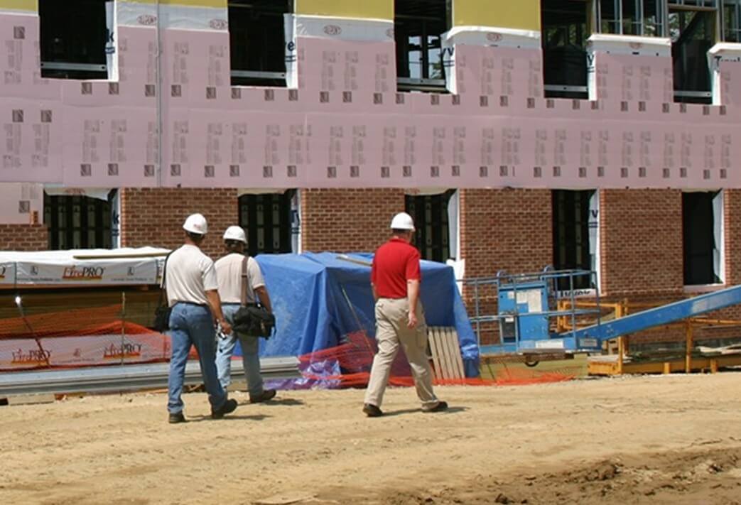 3 men in white construction hats walking towards construction site