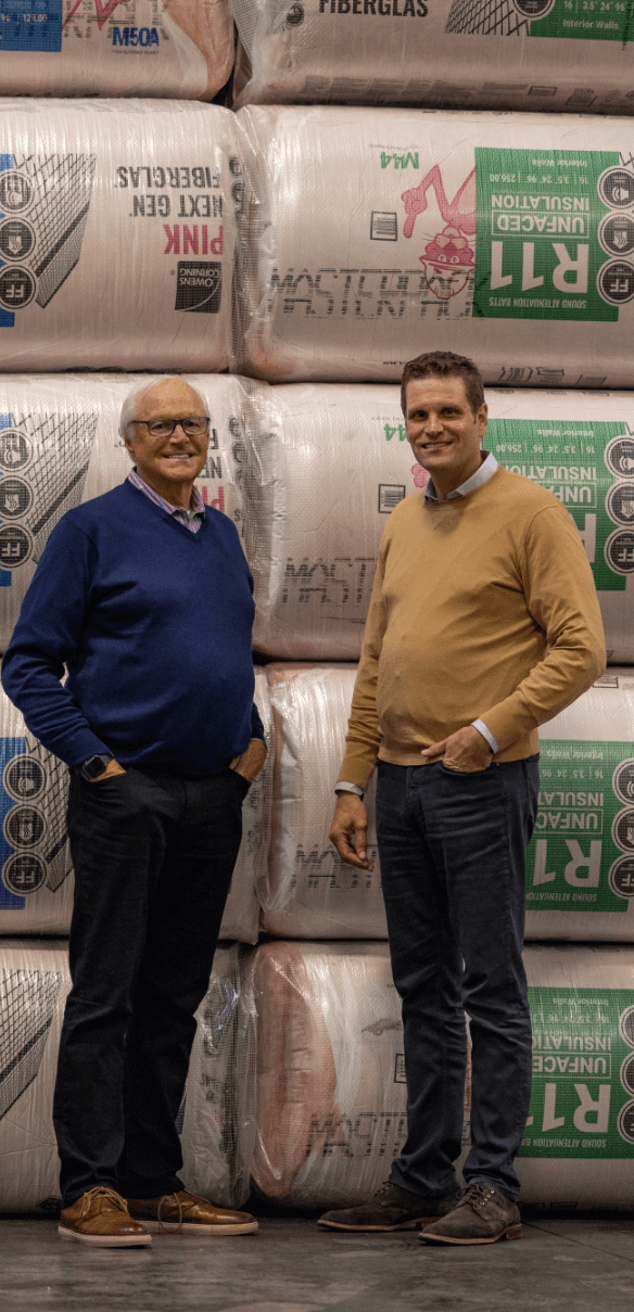 Joe and Chris Novogratz standing in front of giant stack of foam rolls