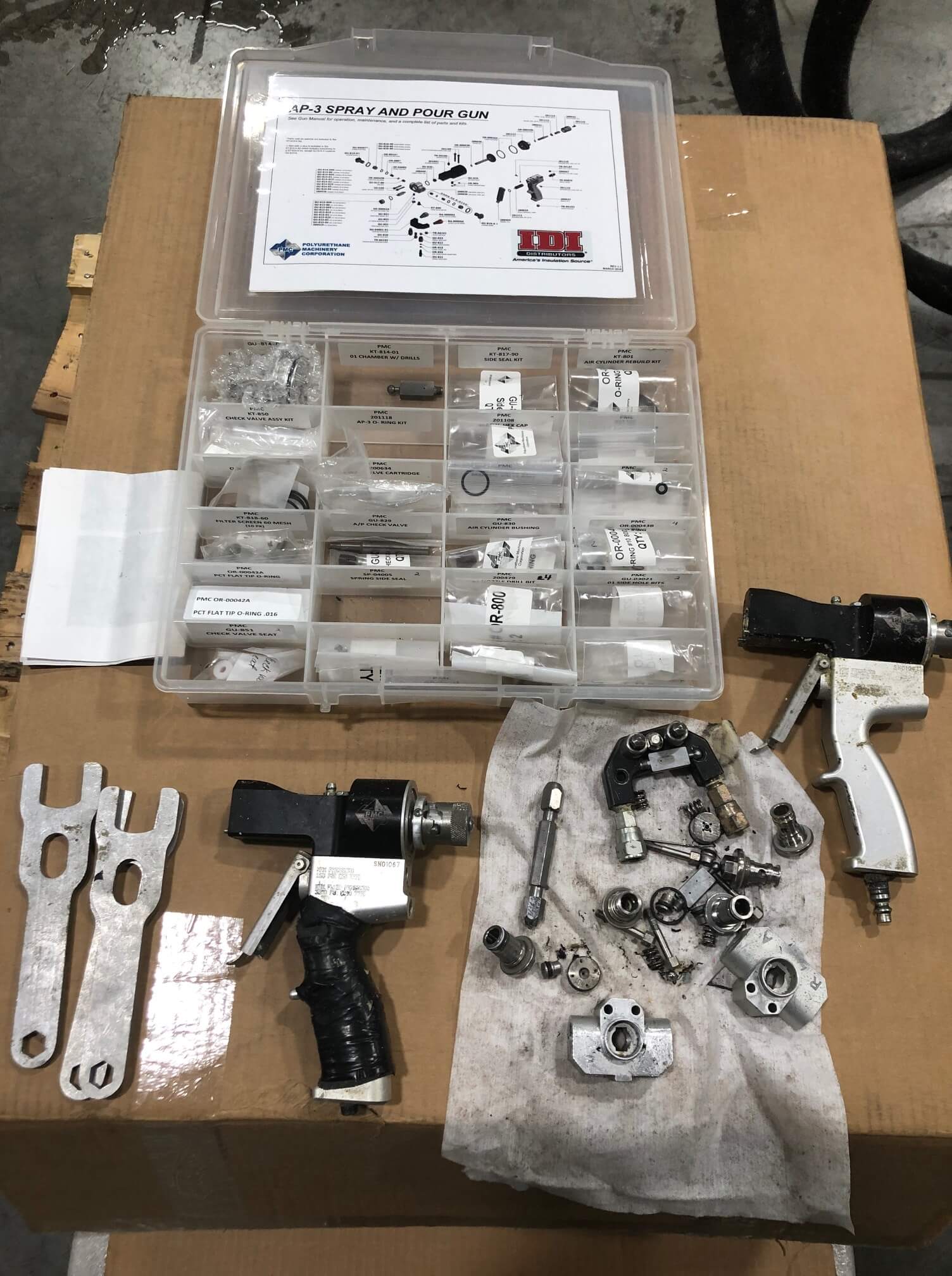 Two spray foam insulation guns taken apart with extra pieces in a case.