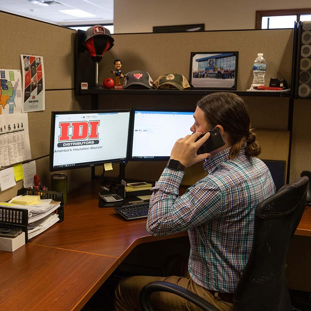 Man answering phone in front of IDI computer