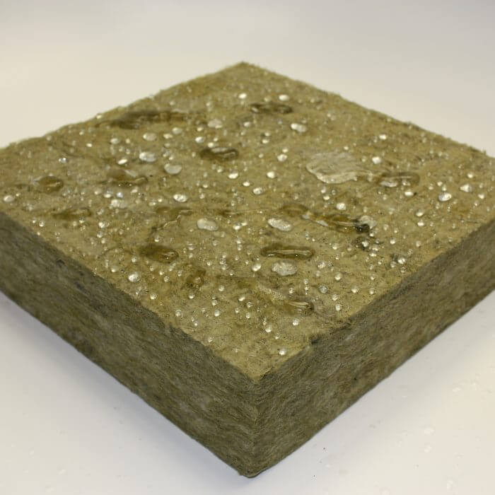 Piece of Thermafiber RainBarrier mineral wool with varying sizes of water droplets on top of it
