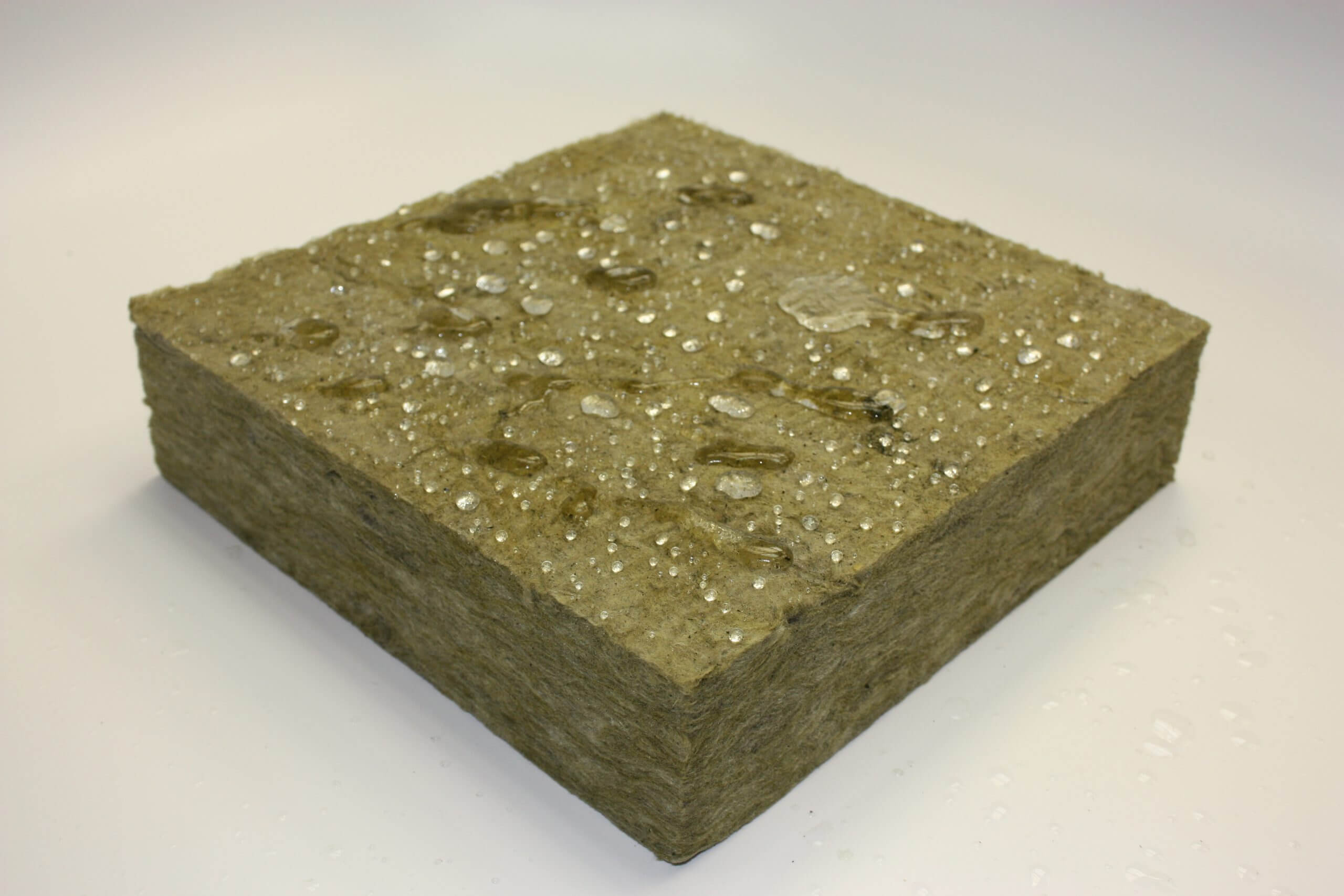 Piece of Thermafiber RainBarrier mineral wool with varying sizes of water droplets on top of it