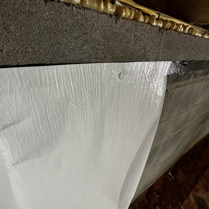 A photo of a crawlspace with Vapor Barrier pins applied to vapor barrier