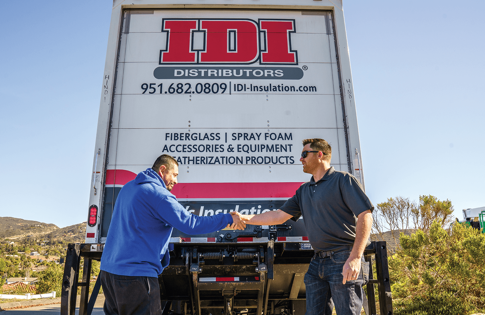 two people shaking hands behind a big rig