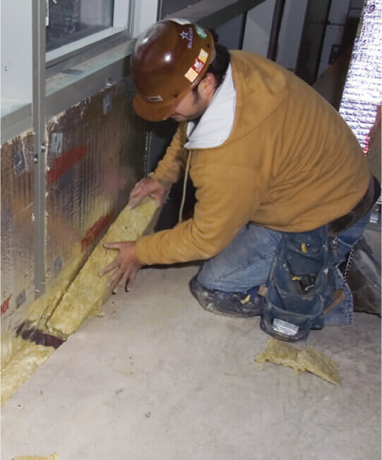 Man in brown work hat laying insulation